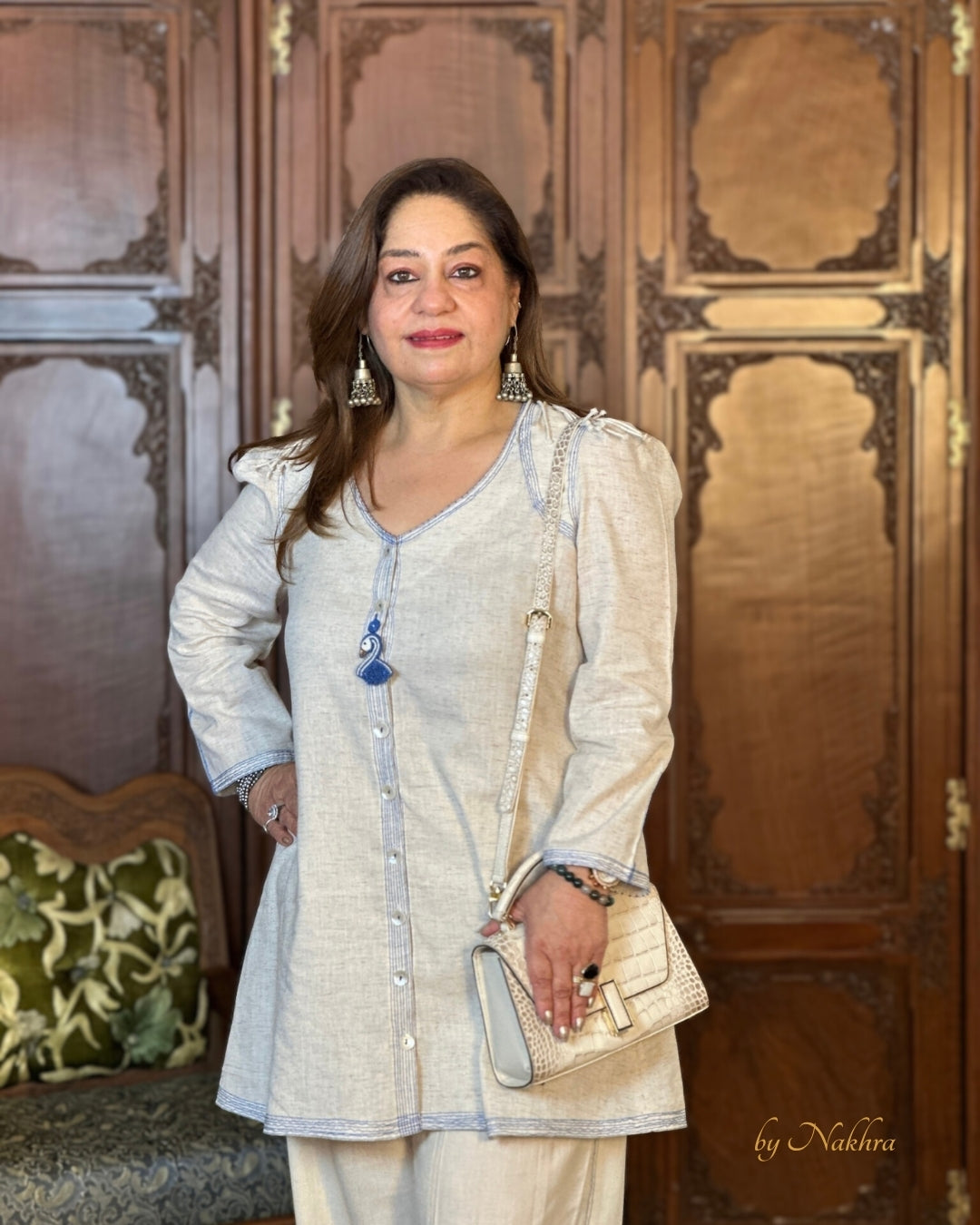 Model posing in First Light co-ord with soft silhouette and refined detailing in ivory khadi fabric paired with a white bag