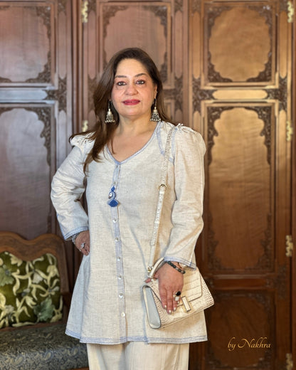 Model posing in First Light co-ord with soft silhouette and refined detailing in ivory khadi fabric paired with a white bag