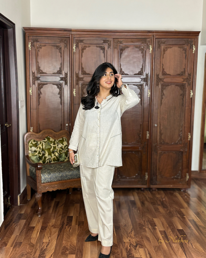 Ivory khadi co-ord set styled with silver clutch side view showing relaxed fit and contrast stitch line